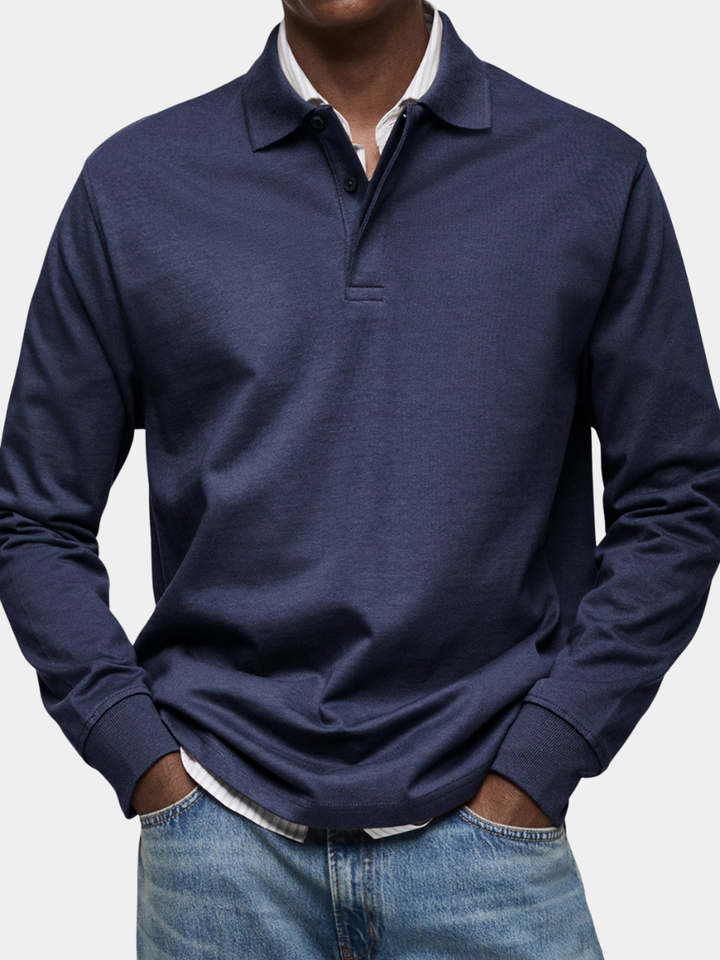 Man draagt het marineblauwe poloshirt met lange mouwen en ribboorden, met handen in de zakken van een spijkerbroek, bijgesneden close-up. 1