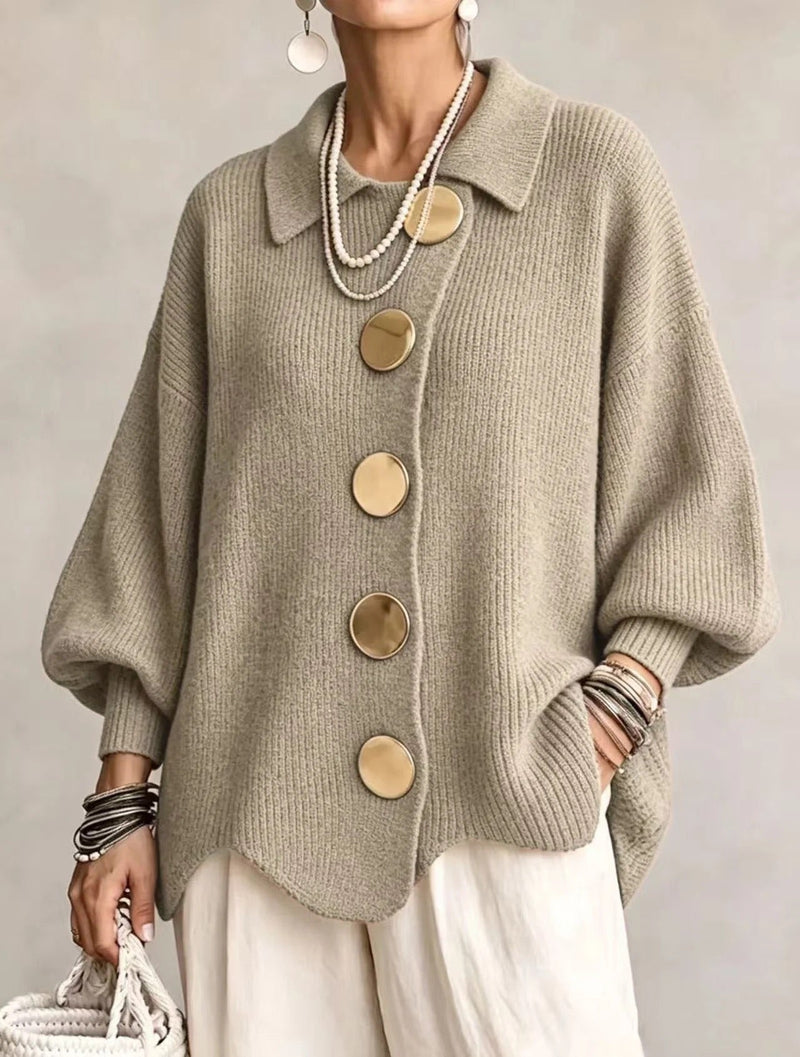 Model draagt het gebreide vest in groenig beige met gouden knopen en een witte broek, vooraanzicht. 17