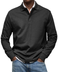 Man draagt het poloshirt met lange mouwen in zwart, met handen in de zakken van een lichtblauwe spijkerbroek. 4