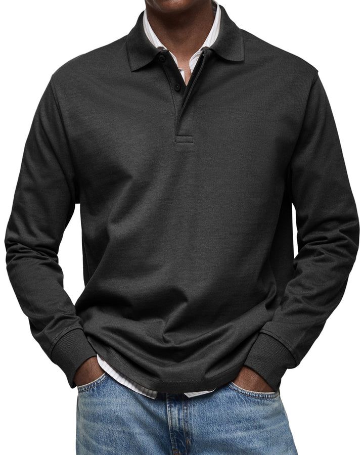 Man draagt het poloshirt met lange mouwen in zwart, met handen in de zakken van een lichtblauwe spijkerbroek. 4
