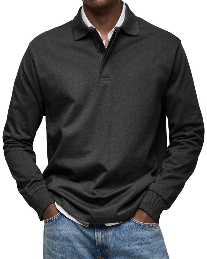 Man draagt het poloshirt met lange mouwen in zwart, met handen in de zakken van een lichtblauwe spijkerbroek. 4