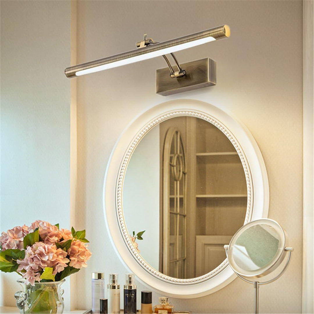 Antiek messing wandlamp met buisvormige ledbalk boven een ovale spiegel met witte rand en toilettafel met bloemen 6