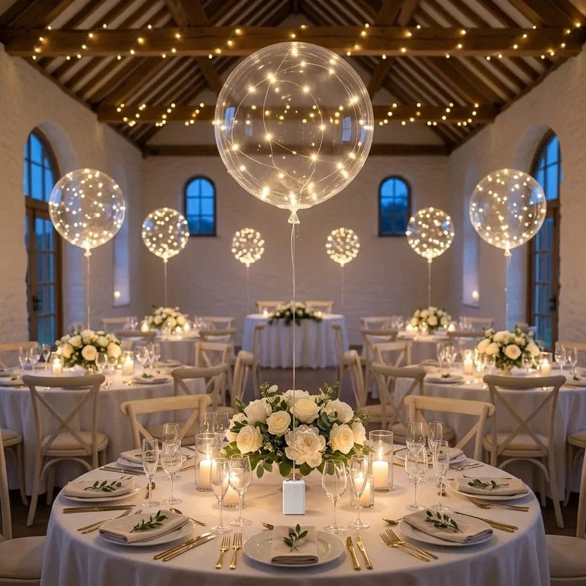 Lichtgevende ballonnen boven ronde tafels met witte bloemstukken in een feestzaal met lichtslingers 5