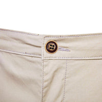 Close-up van de bruine knoop en het knoopsgat aan de tailleband van de beige short. 5