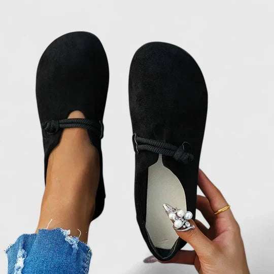 Zwarte loafers, de ene gedragen en de andere in de hand met zicht op de lichte binnenzool 4
