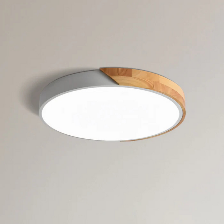 Ronde plafondlamp met witte rand en houten deel, close-up tegen een lichte plafondachtergrond 10