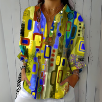 Model draagt de blouse in geel, blauw en paars met abstract patroon, losvallend model met opgerolde mouwen. 5