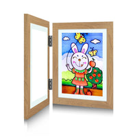 Houtkleurig frame met geopende voorkant en zichtbare metalen scharnieren, met een tekening van een konijn met appels. 3