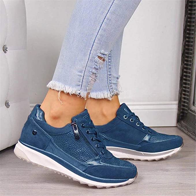 Blauwe sneakers met zijrits en veters, gedragen door een model in een gescheurde lichte spijkerbroek. 3