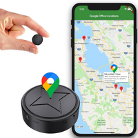 Zwarte ronde mini-tracker met ster op de bovenkant, tussen twee vingers gehouden voor het formaat, naast een smartphone met kaart en locatiemarkeringen. 1