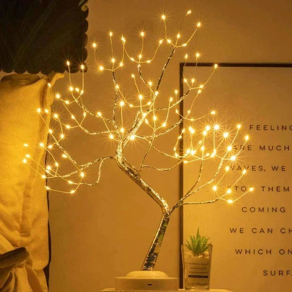 Boomlamp met stralende lampjes in een kamer, naast een klein vetplantje en een ingelijste poster 3