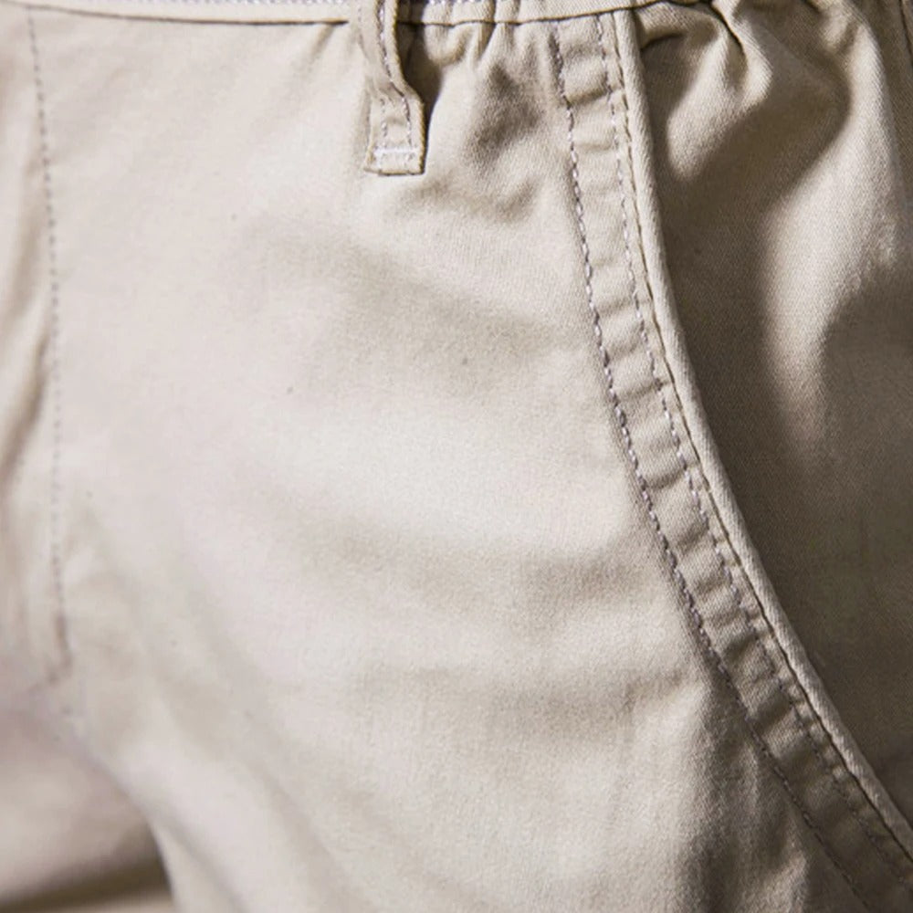 Close-up van de zijzak van de beige short met zichtbare stiksels en een riemlus. 3