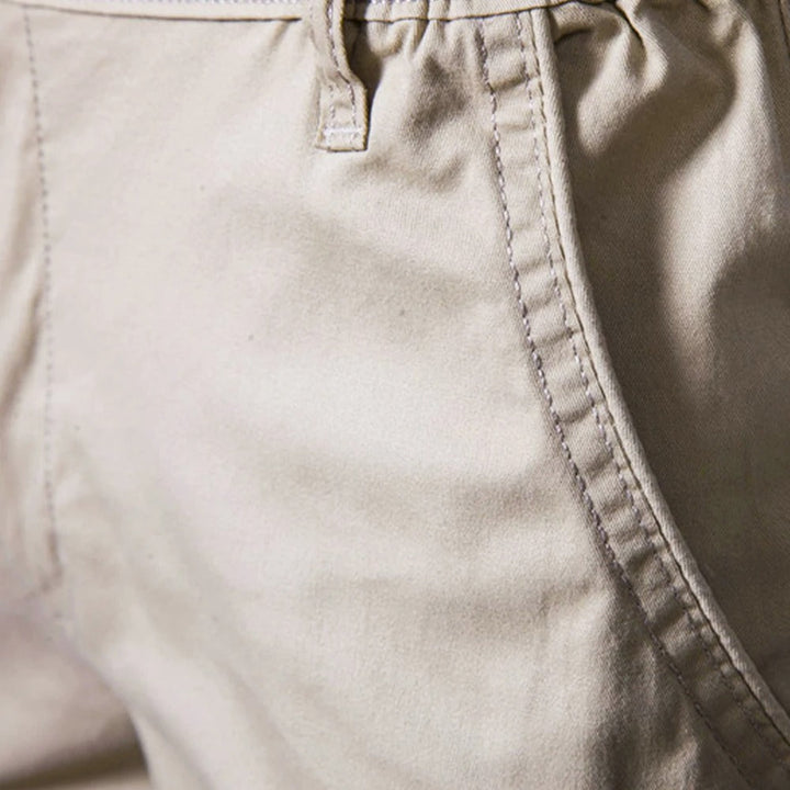 Close-up van de zijzak van de beige short met zichtbare stiksels en een riemlus. 3