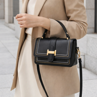 Zwarte tas aan de arm gedragen door een model in beige blazer en crèmekleurige rok, buiten gefotografeerd. 6