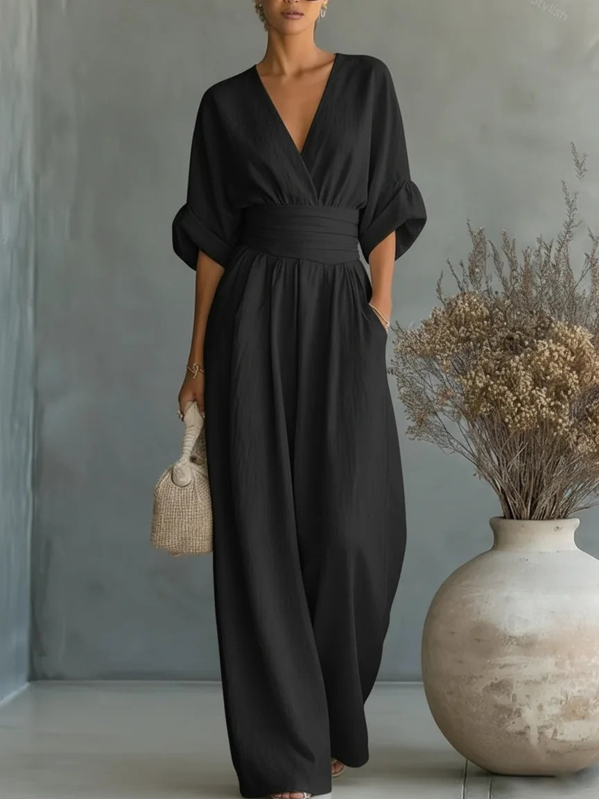 Dezelfde jumpsuit in zwart, van voren gedragen door een model met rieten tasje naast een grote vaas. 5