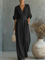 Dezelfde jumpsuit in zwart, van voren gedragen door een model met rieten tasje naast een grote vaas. 5