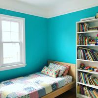 Kinderkamer met turquoise muren, wit plafond en witte raamlijst, bed en boekenkast met kinderboeken 9