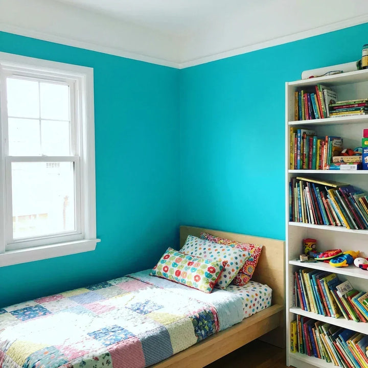 Kinderkamer met turquoise muren, wit plafond en witte raamlijst, bed en boekenkast met kinderboeken 9