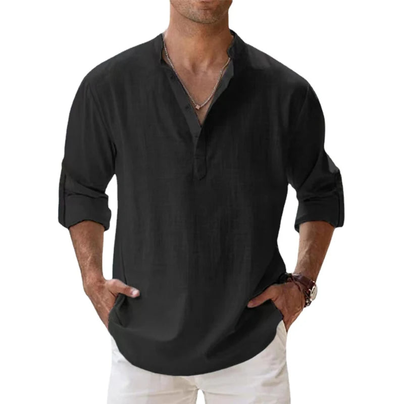 Het henleyshirt in zwart gedragen door een man, met knoopsluiting, opgerolde mouwen en handen in de zakken. 7