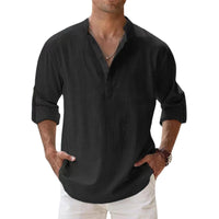 Het henleyshirt in zwart gedragen door een man, met knoopsluiting, opgerolde mouwen en handen in de zakken. 7