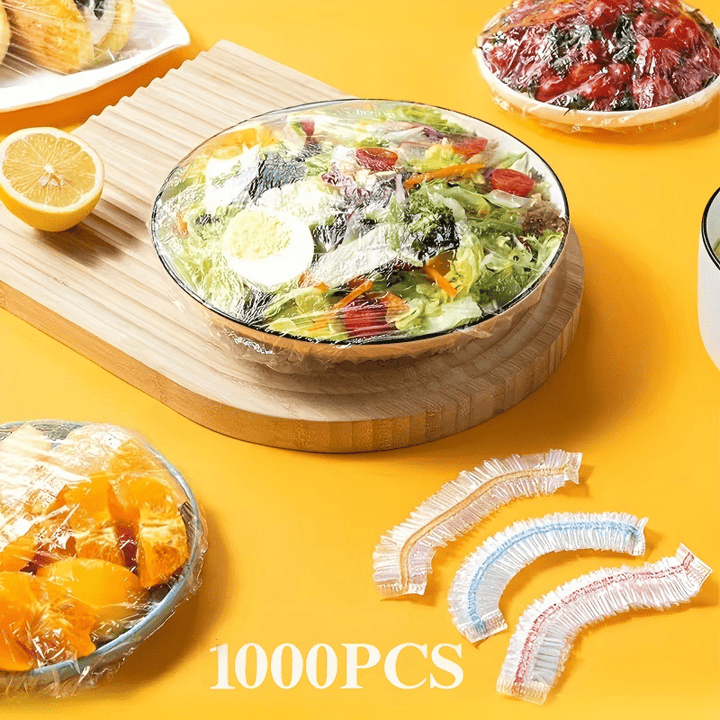 Afgedekte saladekom op een houten plank met gekleurde deksels ernaast, plus afgedekte schalen met fruit op een gele ondergrond. 9