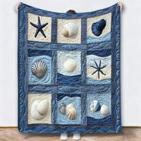 Blauwe deken met schelpen en zeesterren in vakken, omhooggehouden tegen een witte muur 5