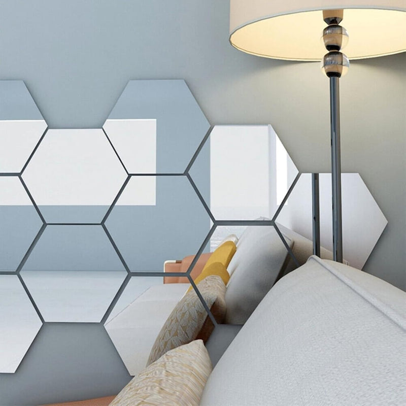 Zeshoekige spiegels aan de muur naast een staande lamp, die een bank met kussens weerspiegelen 6
