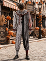 Model in grijs-zwart gestreept clownspak met bloedspatprint en rode pompons, van top tot teen en frontaal gefotografeerd op een herfstachtige straat. 1