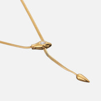 Schuin bovenaanzicht van de platte gouden schakelketting met slangenkop, steentje en druppelvormig uiteinde 2
