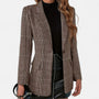 Voorkant van de bruine geruite blazer, open gedragen over een zwarte coltrui en een zwarte kunstleren rok, met klepzakken en een knoop. 1