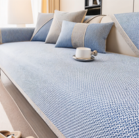 Bankhoes in lichtblauwe stof met fijn geweven patroon, gecombineerd met blauw-beige kussens in een lichte woonkamer. 7