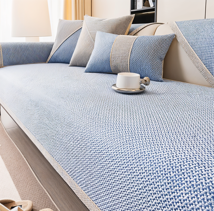 Bankhoes in lichtblauwe stof met fijn geweven patroon, gecombineerd met blauw-beige kussens in een lichte woonkamer. 7