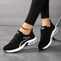 Twee zwarte sneakers met witte zool en witte strepen, gedragen door een zittend model met gekruiste benen. 5