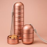 Roségouden aluminium pillendoos, volledig gestapeld naast een korte stapel van twee vakken en een los vakje gevuld met tabletten. 1
