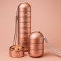 Roségouden aluminium pillendoos, volledig gestapeld naast een korte stapel van twee vakken en een los vakje gevuld met tabletten. 1