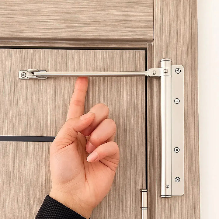 Zilverkleurige deursluiter gemonteerd bovenaan een houten binnendeur, een hand wijst naar de uitgeklapte arm 1