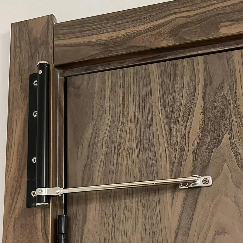 Detail van een zwarte deursluiter met stalen arm op een deur van donker, gemaserd hout 3