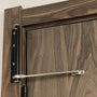 Detail van een zwarte deursluiter met stalen arm op een deur van donker, gemaserd hout 3