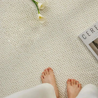 Bovenaanzicht van twee blote voeten op een crèmewitte mat met lage luspool, naast bloemen 6