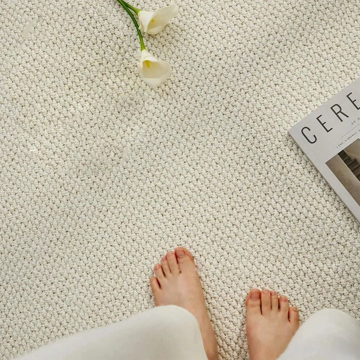 Bovenaanzicht van twee blote voeten op een crèmewitte mat met lage luspool, naast bloemen 6