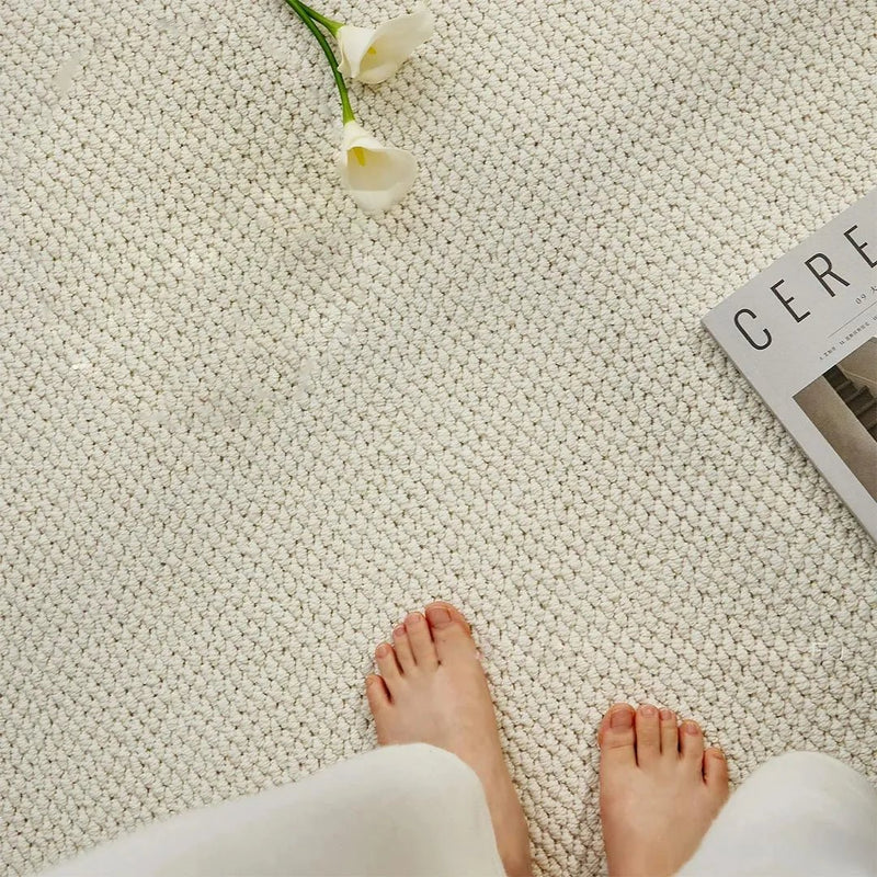 Bovenaanzicht van twee blote voeten op een crèmewitte mat met lage luspool, naast bloemen 6