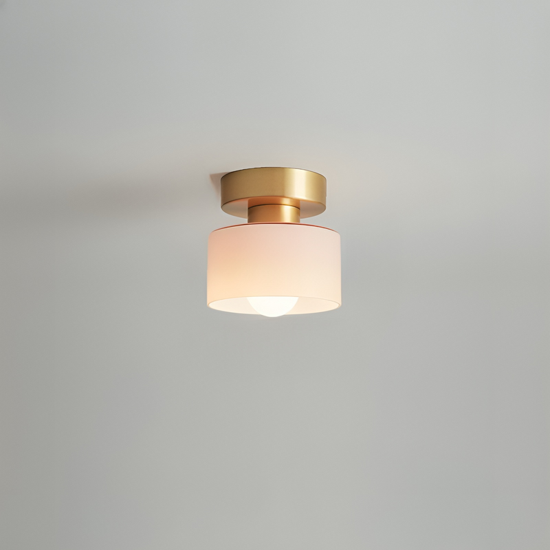 Plafondspot met goudkleurige basis en roze getinte witte kap, brandend tegen een lichtgrijs plafond. 5