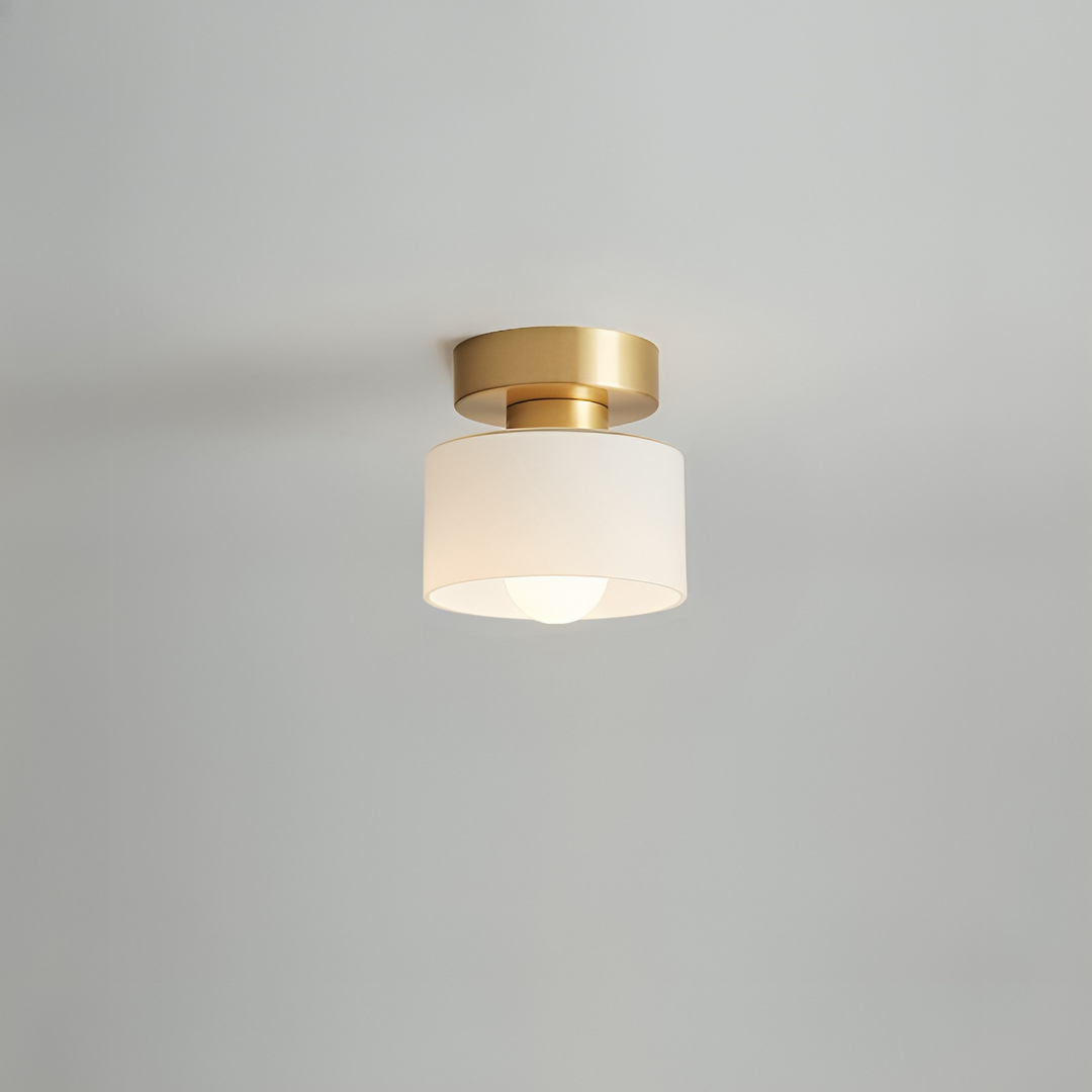 Plafondspot met goudkleurige basis en witte kap, brandend tegen een lichtgrijs plafond. 6
