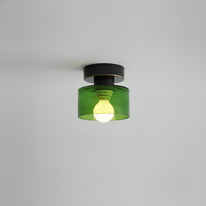 Plafondspot met zwarte basis en groene glazen kap waarin de lamp zichtbaar brandt, tegen een grijs plafond. 10