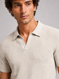 Close-up van de kraag, V-hals en het structuurbreisel van het beige poloshirt 17