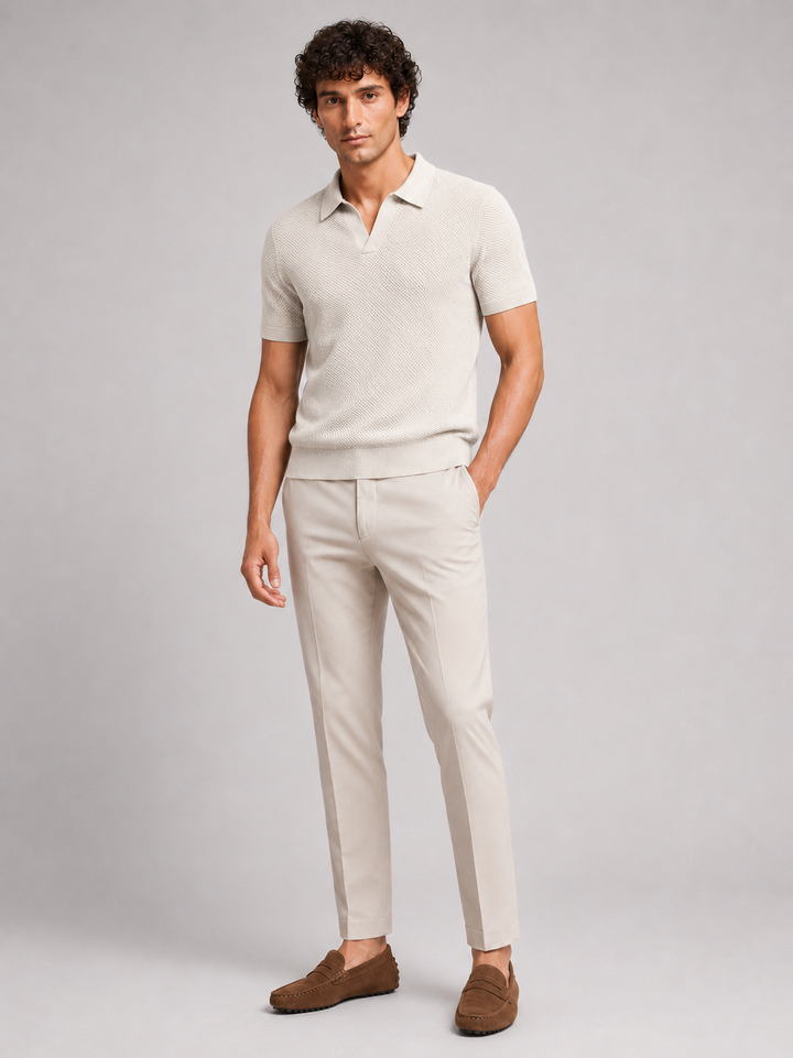 Beige poloshirt in volledig model van voren, gedragen met crèmekleurige broek en bruine suède loafers 18