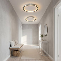 Twee ronde plafondlampen van verschillende grootte branden boven een hal met houten bankje, console en ronde spiegel. 6