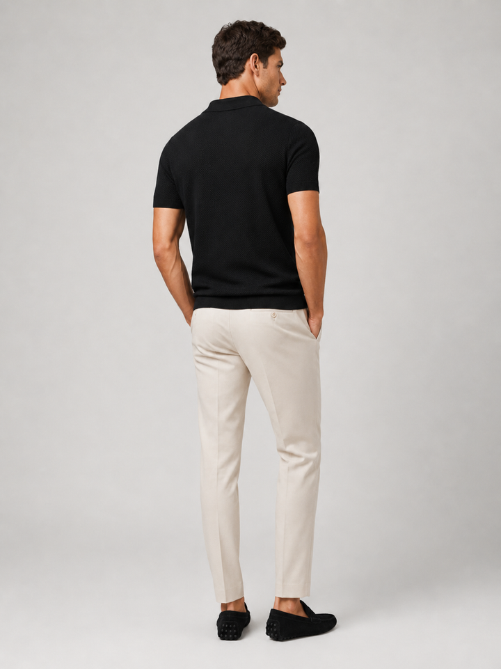 Achterkant van het zwarte poloshirt, gedragen met crèmekleurige broek en zwarte loafers 9