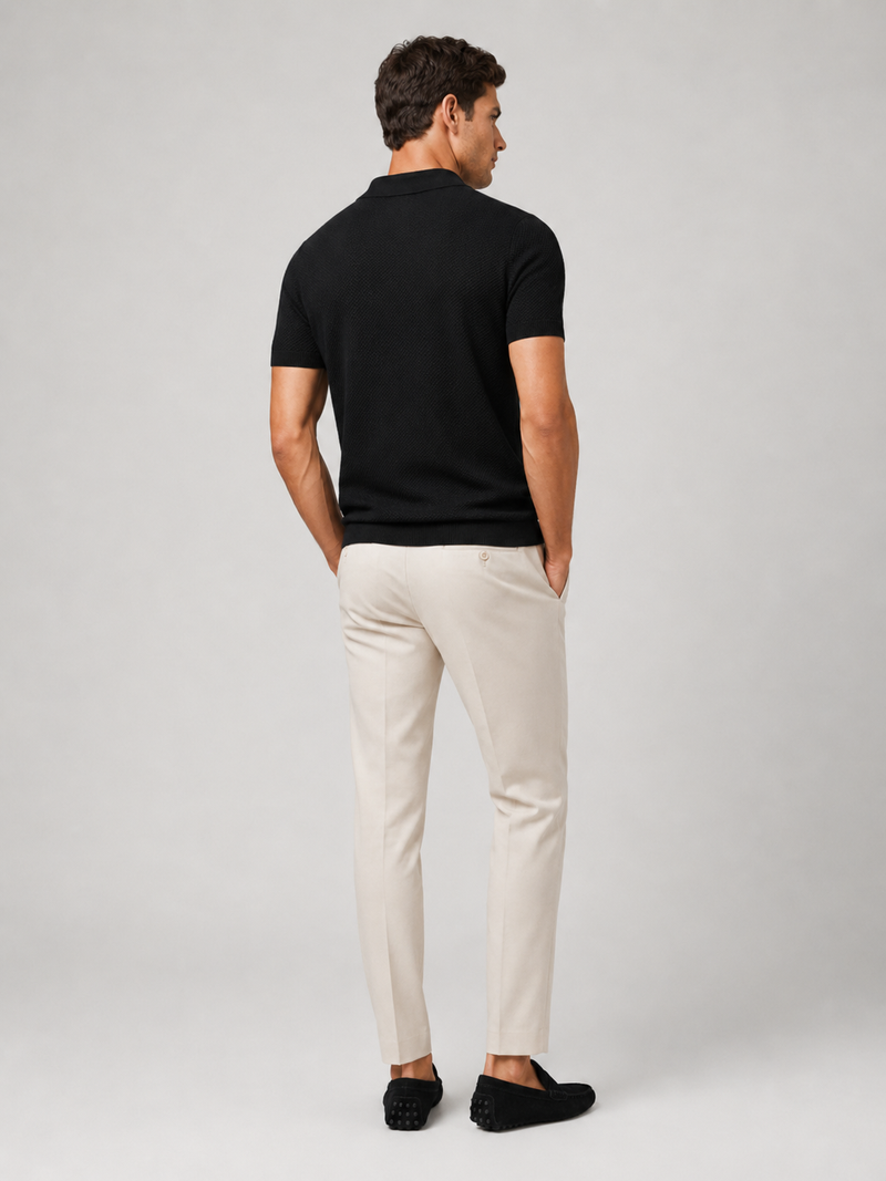 Achterkant van het zwarte poloshirt, gedragen met crèmekleurige broek en zwarte loafers 9