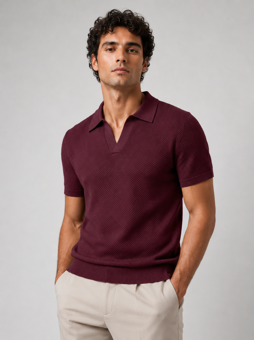 Man in bordeauxrood gebreid poloshirt met V-hals, handen in de zakken van een beige broek 21